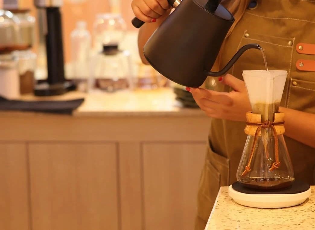 Barista sirviendo agua caliente sobre un filtro de café en Uriarte Barra