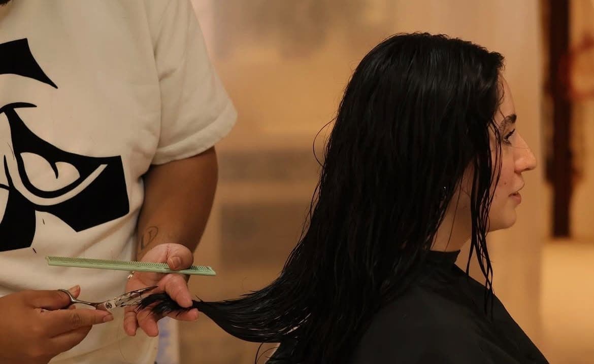 Estilista cortando las puntas de cabello largo y húmedo