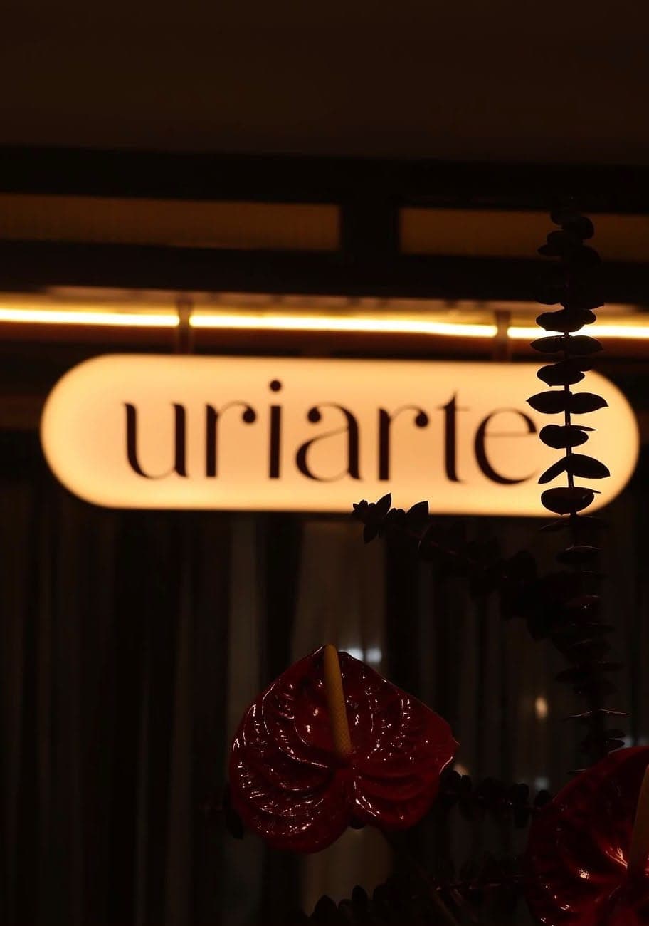 Letrero luminoso de Uriarte entre flores de anturio